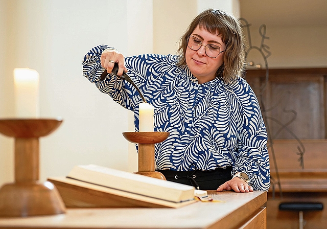 Mit ruhiger Hand bringt Daniela Schneuwly die Altarkerzen zum Leuchten.Bild: Manuel Arnold