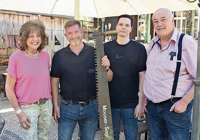 Alt und neu vereint: Heidi Mosimann (links) und Oskar «Oski» Urech (rechts) übergeben die «Moosersagi» symbolisch mit der Säge an ihre Nachfolger Sandro Boll und Martin Röthlisberger, die das Gasthaus Ende 2026 übernehmen.Bild_ Raphael Nadler